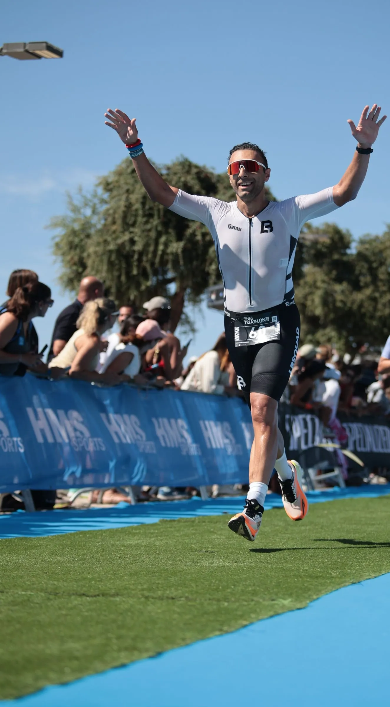 Shahin crossing a triathlon finish line with both arms raised